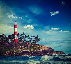 Vintage retro hipster style travel image of old lighthouse and waves of sea. Kovalam