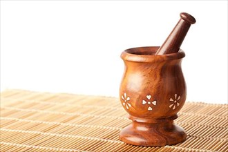 Wooden mortar with pestle on bamboo mat