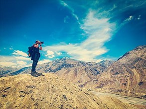 Vintage retro effect filtered hipster style image of photographer taking photos in Himalayas mountains. Spiti valley