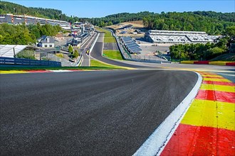 View from low perspective of 40 metres high hilltop above from front steep driveway Raidillon on behind it curve Mutkurve Eau Rouge of race track Spa Francorchamps without vehicles racing cars
