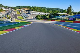 View from the centre of the racetrack to the 40-metre-high hilltop above the steep Raidillon ramp in front and the dangerous Eau Rouge bend behind it on the Spa Francorchamps racetrack without racing ...
