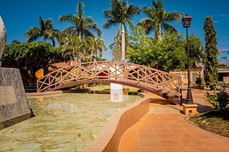 Side view of a small wooden bridge over a water fountain in a calm park. Nagarote central park. View of a nice and relaxed park with a water fountain. Traditional park of Nagarote