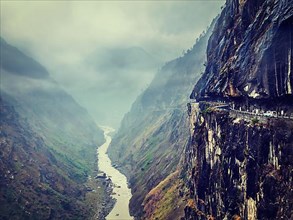 Vintage retro effect filtered hipster style image of car on dangerous road in Himalayas mountains in gorge above precipice