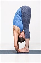 Sporty fit woman practices yoga asana Padahastasana
