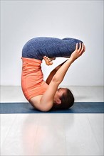 Sporty fit yogini woman practices inverted yoga asana Urdhva padmasana