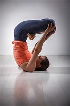 Sporty fit yogini woman practices inverted yoga asana Urdhva padmasana