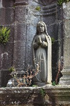 Praying statue next to the church of Saint Derrien