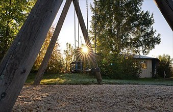 Children's swing with sun star at sunset