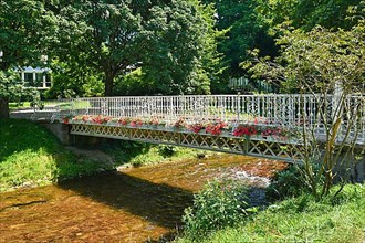 Beautiful bridge over river Oos with flowers in park called 'Lichtentaler Alle' in health resort Baden-Baden in Germany