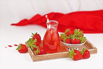 Strawberry fruit lemonade in jar surrounded by berries on wooden tray