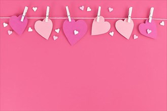 Pink paper hearts hanging from line with pegs and sugar sprinkles