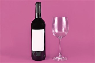Wine bottle with blank label next to empty wineglass on burgundy background