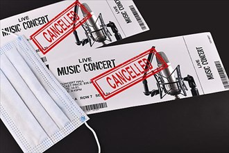 Concept for cancelled entertainment events during Corona virus pandemic with concert tickets and red cancelled stamp on them and face mask