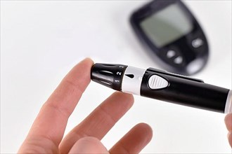 Pricking finger with lancing device used by diabetic person for checking blood glucose sugar level