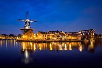 View of Harlem cityscape with landmark windmill De Adriaan on Spaarne river in the night illuminated. Harlem