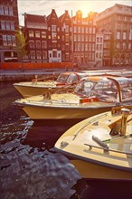 Amsterdam tourist boats in canal on sunset. Amsterdam