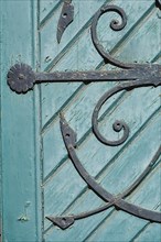 Old decorated iron door fitting on an old green wooden door