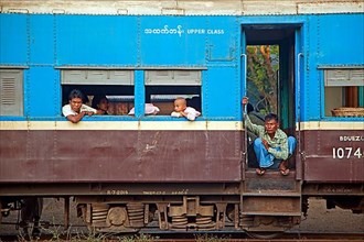 Burmese passengers in the blue upper class car of an old British train in Myanmar