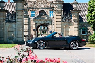 Woman with Porsche 911 cabriolet in front of castle