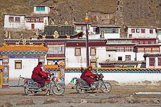 Two Tibetan monks on motorbikes in front of a monastery between Sershu Dzong and Sershu