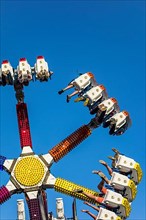 Excited thrillseekers have fun on the G Force funfair attraction at the travelling funfair