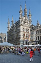 Tourists in sidewalk cafes in front of the Gothic City Hall at the Grote Markt