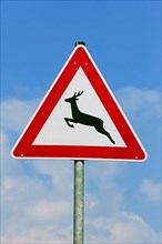 Deer crossing the road game warning sign against blue sky