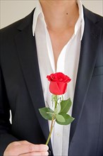 Man in a suit holding a red rose