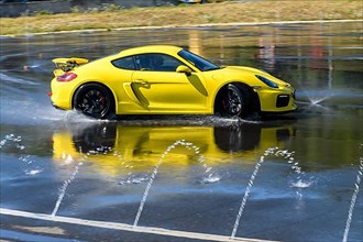 Sports car racing car Porsche Cayman GT4 on rain track drifting drifting across wet asphalt during driving safety training