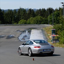 Porsche 911 997 Carrera sports car takes off to retain control during slalom course at driving safety training
