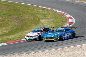 BMW M235i Racing is overtaken on the outside by Mercedes-AMG GT3 at 24h Nuerburgring race track 24-hour race