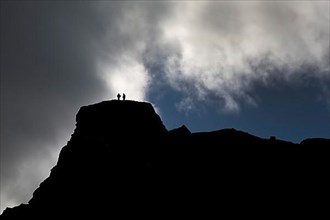 Dramatic sky with two people in front of clouds on a mountain in Kirkjubaejarklaustur