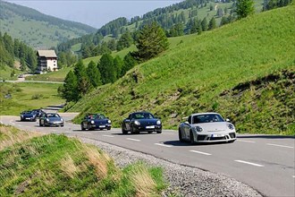 Six Porsche 911 sports cars on mountain road in high Alps near Col de Vars