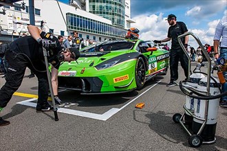 Race team prepares Lamborghini Huracan GT3 race car on start-finish straight gridlane for start of car race