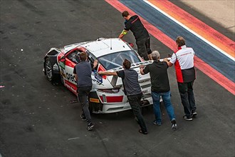 Racing team pushes Porsche 911 GT3 race car to pit lane