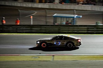 Race car Ford Mustang at night at car race 24-hour race 24h race on Grand Prix track of Nuerburgring race track with glowing brake discs