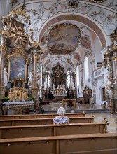 A woman sitting in the rococo church of St. Ulrich in Seeg