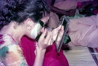 A Katakali artist applying makeup
