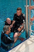 Disabled diver lowered into swimming pool by chairlift