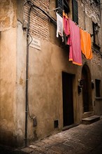 Laundry hanging along a narrow cobblestone street