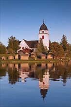 The picturesque old church of Raettvik surrounded by horse stables at Lake Siljan