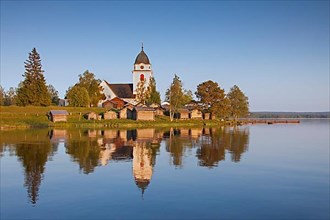 The picturesque old church of Raettvik surrounded by horse stables at Lake Siljan
