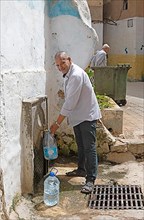 Moroccan man fetching drinking water at a standpipe
