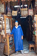 Moroccan man in a traditional djelabba or hooded coat at the entrance to his shop