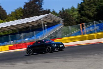 Racing car sports car Audi TT races at high speed full throttle at exit of bend hairpin La Source of racetrack