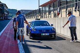 Blue Porsche 911 992 GT3 at trackday awaits clearance from race marshal to exit pit lane onto circuit