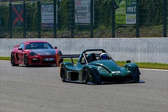 Radical SR10 open-wheel racing car in front behind Porsche Cayman GT4 races at high speed top speed during trackday on start-finish straight of race track