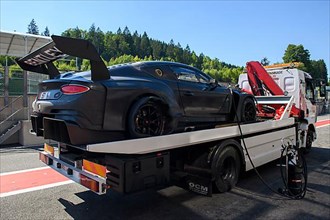 Bentley GT3 race car is brought back to pit lane Pit Lane of circuit by tow truck after puncture with blown right rear tyre