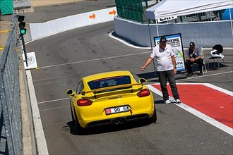Race car Sports car Porsche Cayman GT4 at trackday gets green light from traffic lights Clearance from race marshal for exit from pit lane Pit lane on circuit for car racing
