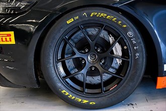 Racing tyres with markings of racing mechanic lettering mounted on racing car in pit of racetrack for car racing